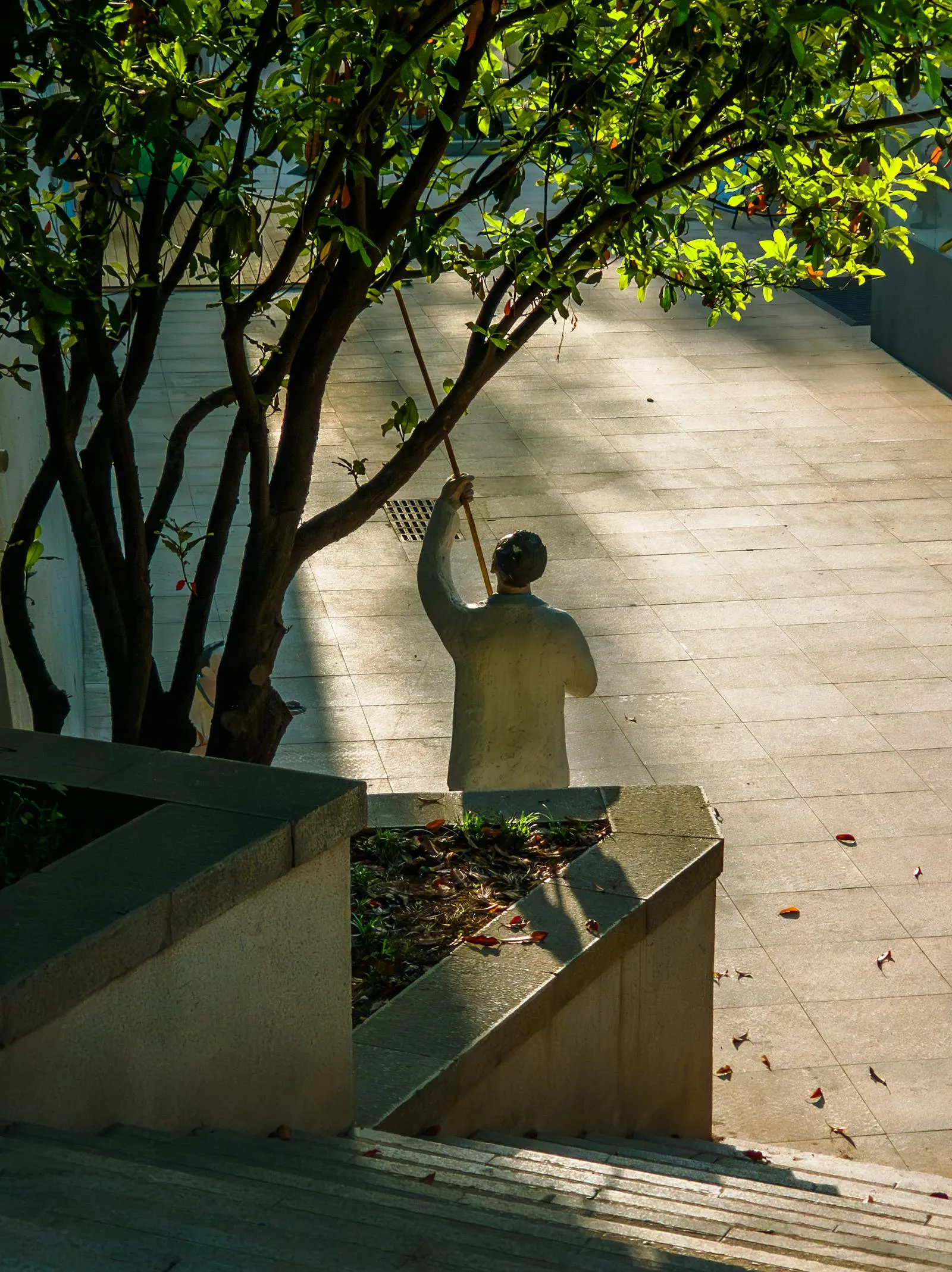 Worker raking debris from a courtyard during a yard cleanup.