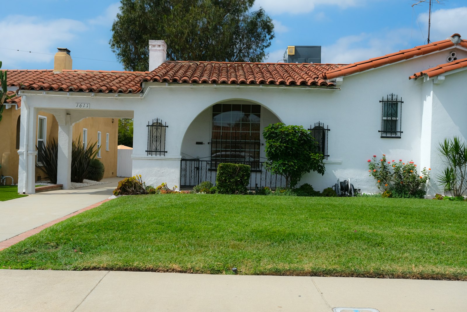 Phoenix stucco home with tile roof, neat front gravel bed, and trimmed bushes.